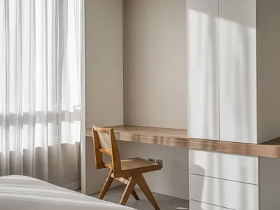 Minimalist bedroom featuring a wooden desk and white curtains