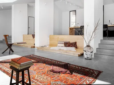 A minimalist living room features wooden benches and a large rug in a modern space.