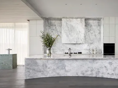 A modern kitchen featuring marble countertops and backsplash with minimalist design.
