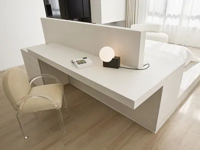 Modern, minimalist bedroom with a concrete platform bed and glass chair.