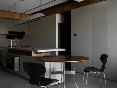 Modern kitchen with minimalist design, featuring a wooden table, black chairs, and a wood-and-metal kitchen island.