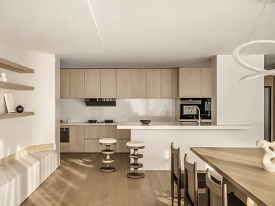 A minimalist residential kitchen featuring wooden finishes, white countertops, and modern appliances.