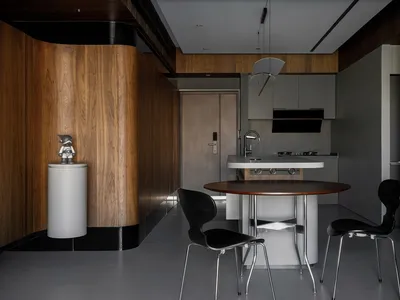 A modern kitchen with wood panel walls and a circular dining table.