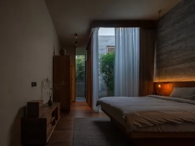 A minimalist bedroom featuring natural wooden furniture and soft, neutral textiles