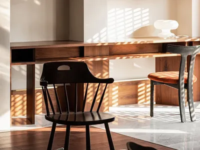 Modern home office space featuring a wooden desk with seating arrangements and decorative items.