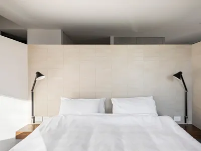 A minimalist white bedroom with modern design elements.