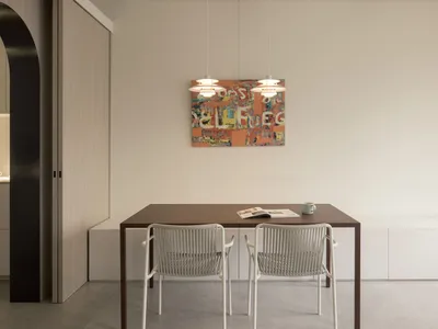 Modern kitchen with wooden table and chairs, featuring minimalist design elements.