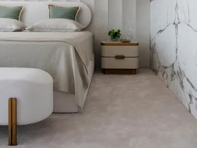 A modern bedroom featuring a neutral-toned color palette, plush bedding, and minimalist decor.