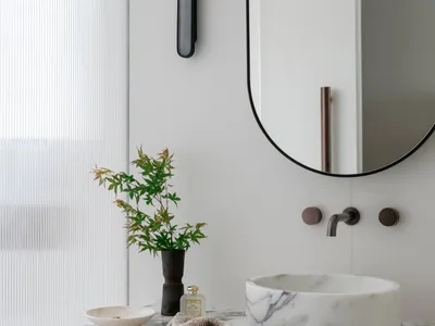 A minimalist bathroom featuring a marble counter with a vase, bowl, and towel hanging on it.