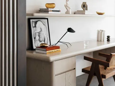 A minimalist home office featuring wooden shelves and a desk with various decorative objects and books.