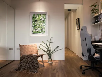 A modern, minimalist home office featuring a wooden chair and a desk with a computer.