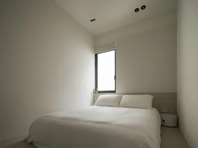A minimalist bedroom featuring a large bed with white bedding and a neutral color palette.