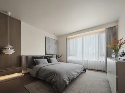 A minimalist bedroom with a gray fabric bed, white curtains, and a modern hanging light fixture.