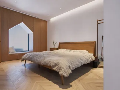 Minimalist bedroom with wooden furniture and light-colored bedding.
