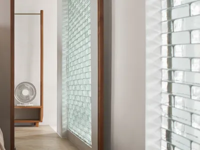 A minimalist bedroom featuring wooden furniture, glass partition, and metallic fixtures.