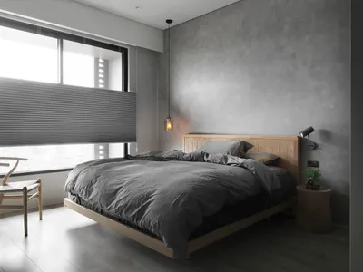 簡約臥室內有混凝土牆面、木質床架與灰色寢具。