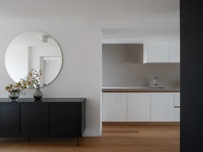 A modern minimalist kitchen with a concrete finish and white cabinets.