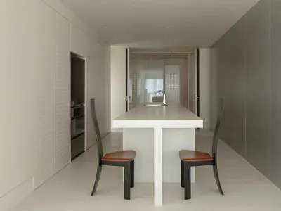Modern minimalist kitchen with white concrete countertop and black chairs.