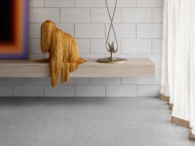 Minimalist living room featuring a concrete counter with a modern lamp and a textured golden throw