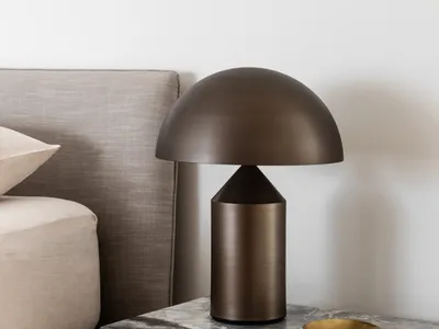 Modern bedroom featuring a marble nightstand with a stylish table lamp and a comfortable upholstered bed.