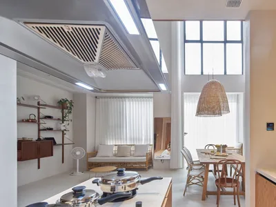A modern living/dining/kitchen space with a minimalist design, featuring wicker furniture, a wooden dining table, and an acry