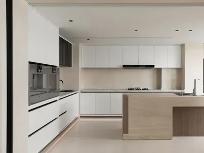 A modern, minimalist kitchen with sleek, white cabinetry and a central island.