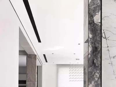 Modern, spacious living room with marble floor, a unique black and white striped lounge chair, and a small, elegant side tabl