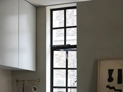 Modern minimalist kitchen featuring a concrete countertop and flooring, with a sleek stainless steel sink and a large window