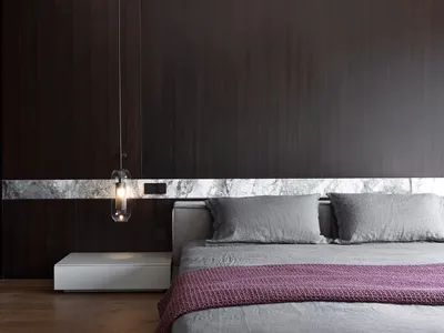 A minimalist bedroom with wooden walls, a grey bed, and a purple throw blanket.