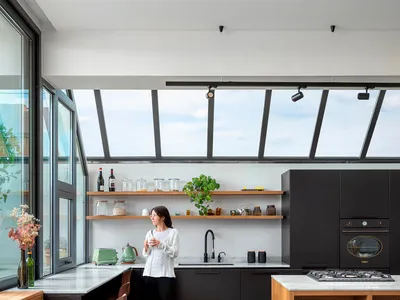A modern kitchen featuring a combination of marble countertops, wooden cabinetry, and concrete flooring.