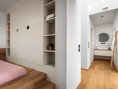 Minimalist bedroom with wooden floors, white walls, and built-in shelves.