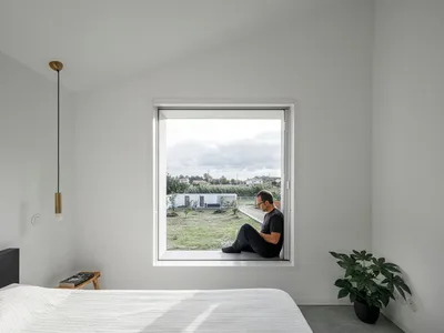 A minimalist bedroom with a bed, window, and green plant.