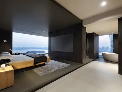 A sleek, minimalist bedroom featuring concrete and glass materials, with a large window overlooking the cityscape.