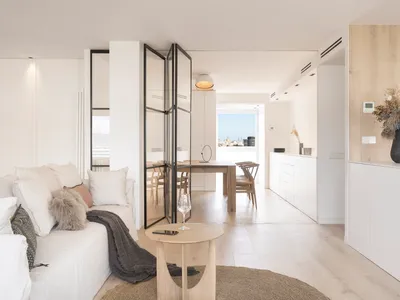 A modern minimalist kitchen with white cabinets and wooden accents.