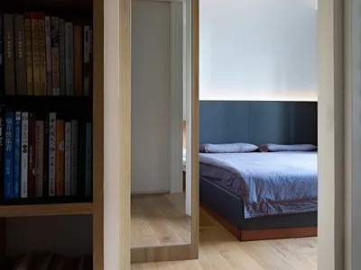 A minimalist bedroom with wooden furniture and a blue bedspread.