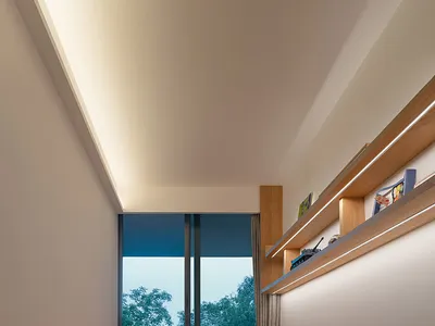 A minimalist bedroom featuring wooden furniture and a large window with a view of trees.