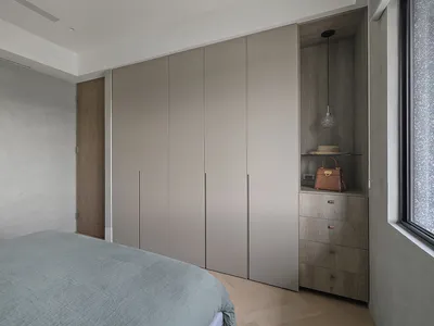 Modern minimalist bedroom featuring a bed with gray bedding and a large closet with gray panels.