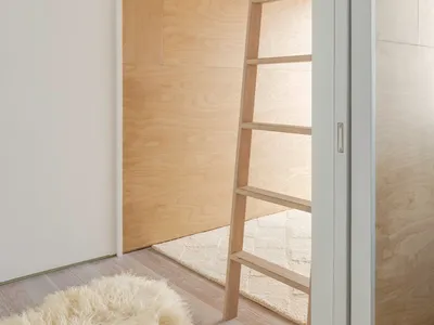 A minimalist bedroom featuring a wooden bunk bed with a ladder.