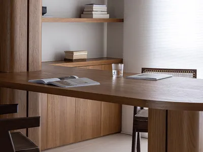 Modern minimalist home office featuring a wooden desk with a glass pendant light and white sheer curtains.