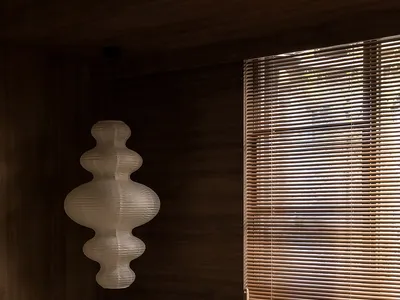 A minimalist bedroom featuring wooden accents, a window with blinds, and a lamp with a geometric design.