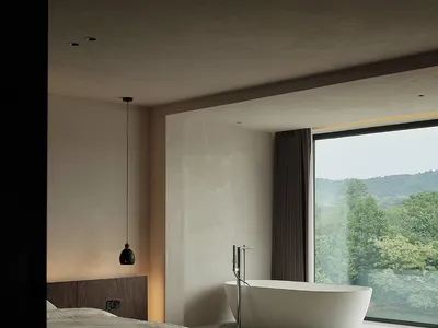 現代極簡臥室，鋪設混凝土地板，浴缸旁設有大窗，可眺望山景。