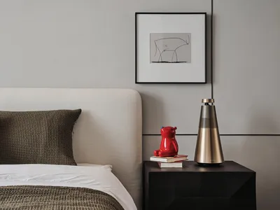 Minimalist bedroom with a bed featuring a white upholstered headboard, brown and beige textured bedding, and a wooden bedside
