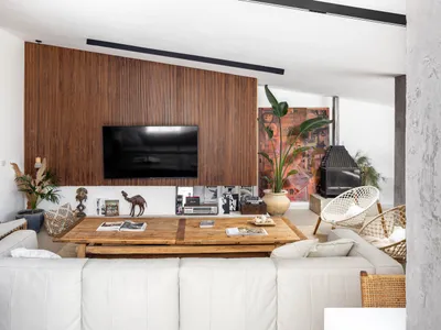 A modern industrial living room with a wooden wall, leather furniture, and a large screen TV.