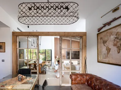 A spacious, open-concept living room with industrial design elements, featuring woven-wood paneling, a large leather sofa, an