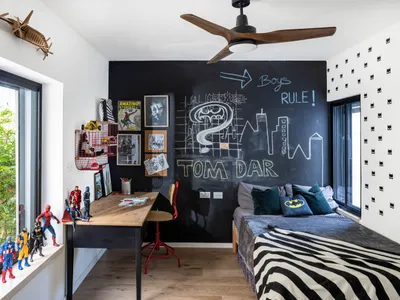 A modern, black and white themed bedroom with a chalkboard wall, a bed with zebra print bedding, and superhero figurines on t