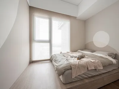 Modern minimalist bedroom featuring a light wood bed frame and soft, neutral bedding.