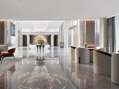 A modern hotel lobby with marble floors and white and brown furniture.