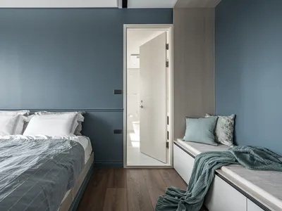 Minimalist bedroom with a bed, bench seat, and wooden floors.