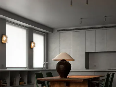 Modern kitchen interior featuring a wooden table with a lamp and green chairs.