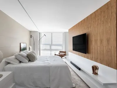 A modern bedroom with minimalist design featuring a white bed and wooden accents.